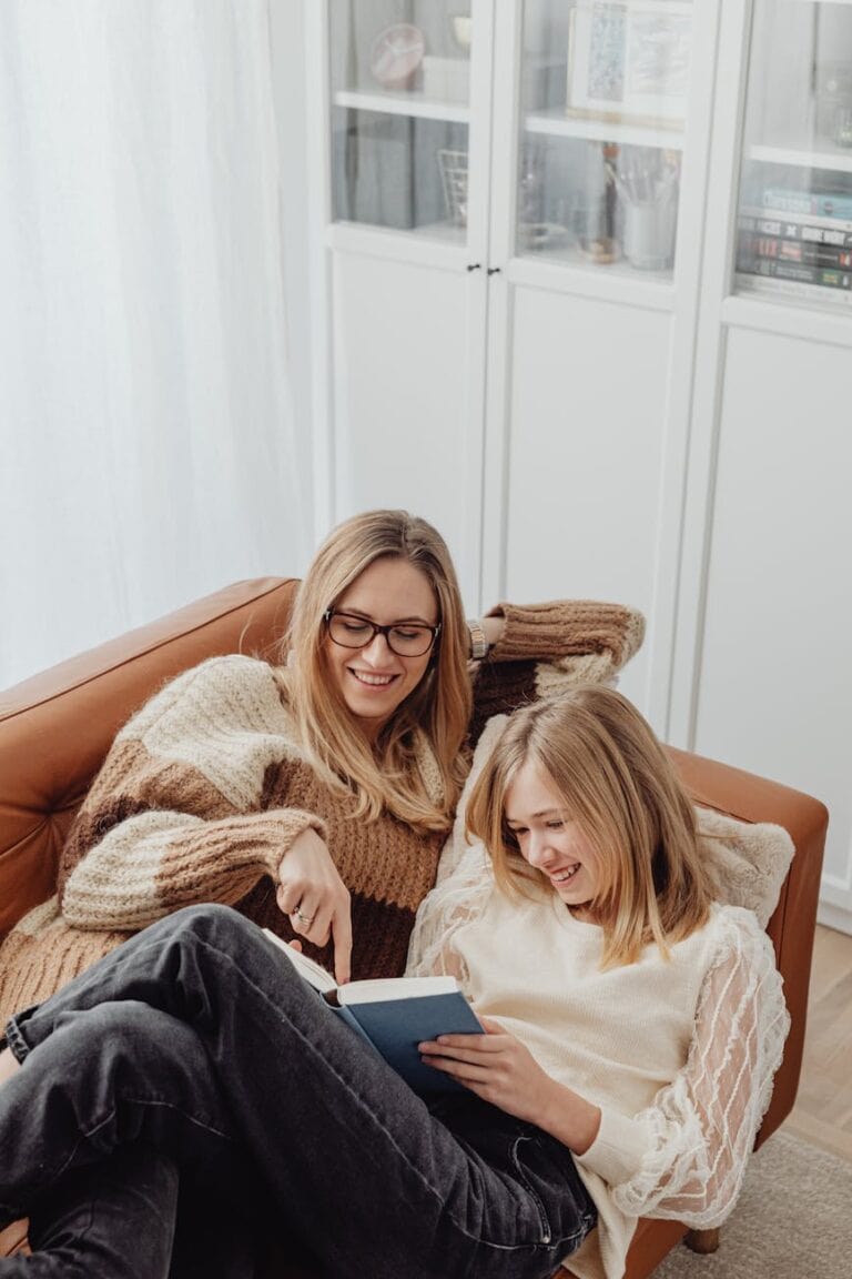 women lying on the couch while reading a book
